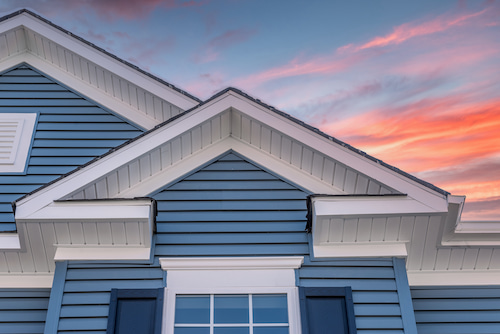 Close-up of blue lap siding with white trim at sunset